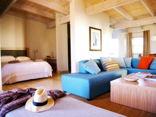a living room with a blue couch and a bed at The Cottage Collection Paternoster in Paternoster