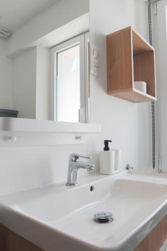 une salle de bain avec un lavabo blanc et un miroir dans l'établissement Le Spot, proche Euroairport, à Saint-Louis