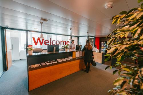 a woman standing in front of a welcome sign in a store at SwissTech Hotel in Lausanne