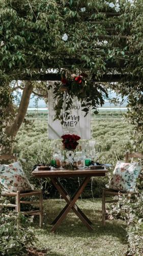a picnic table with flowers on it under a tree at Avoca River Cabins in Addo