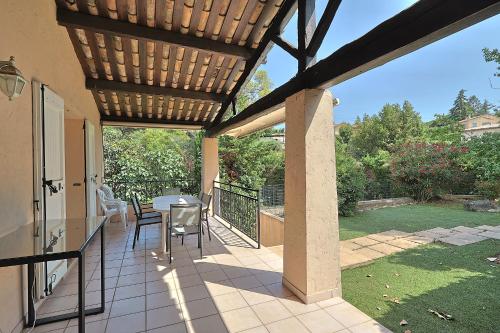 un patio avec une table et des chaises sous une pergola dans l'établissement Villa climatisée de 195 m2 avec piscine privée, à Vallauris