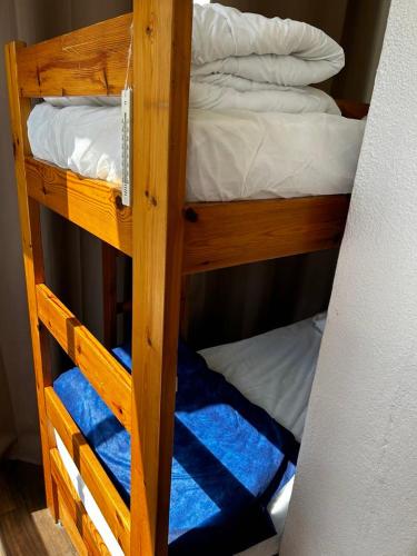 un lit superposé en bois avec deux lits superposés avec des serviettes bleues dans l'établissement Cocon et bien-être en bord de mer, à La Grande Motte