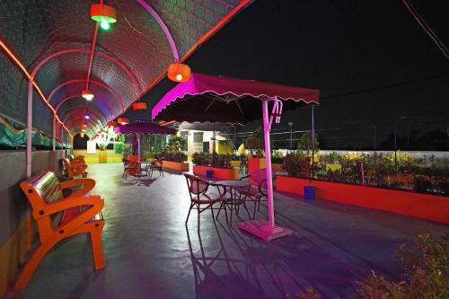 a patio with tables and chairs and an umbrella at PS Luxury Hotel in Baharampur