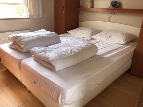 twee bedden met witte lakens en kussens erop bij Kustverhuur, Groede, Paarlhof 29 in Groede