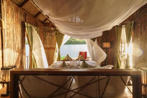 a bed in a room with a view of the water at Thansur Tatai Eco Resort in Tatai
