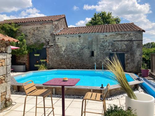 un patio extérieur avec une table et des chaises à côté d'une piscine dans l'établissement Le domaine de la Rabatelière, à Saint-Colombin