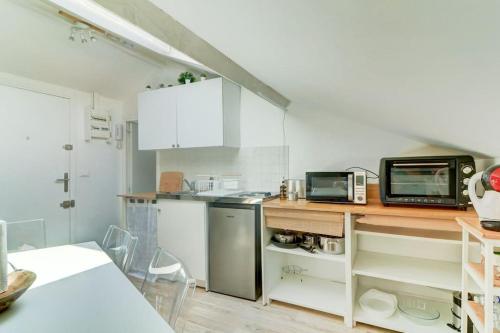 une cuisine avec des placards blancs et un comptoir avec un four micro-ondes dans l'établissement Joli loft mansardé, à Nice