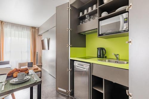 a small kitchen with a sink and a table at Appart’City Confort Le Bourget - Aéroport in Le Bourget