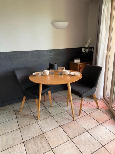 a wooden table and two chairs in a room at Appartement Le Beach du Lac d'Annecy avec les pieds dans l eau, plage et ponton privé in Duingt