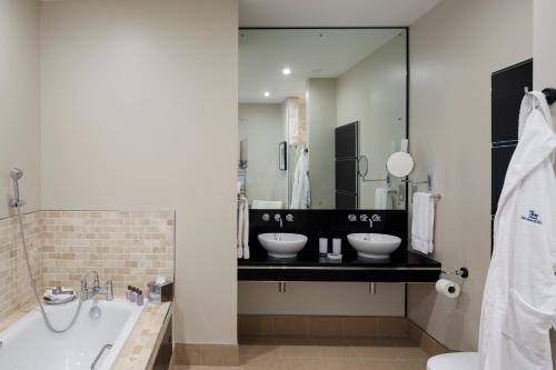 a bathroom with two sinks and a large mirror at Bowood Hotel, Spa, and Golf Resort in Chippenham