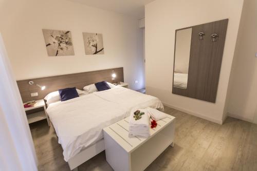 a bedroom with a white bed and a mirror at Hotel Roma Aparthotel in Malcesine