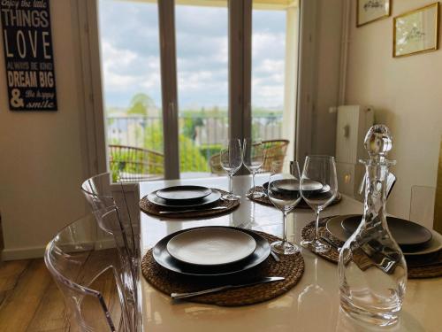 - une table à manger avec des assiettes et des verres à vin dans l'établissement Yucca, Appartement avec garage privé et balcon, à Caen