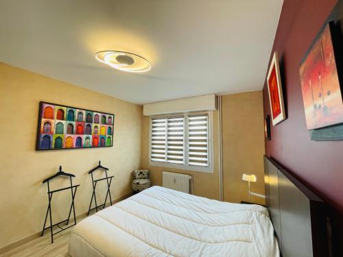 a bedroom with a bed and a painting on the wall at Yucca, Appartement avec garage privé et balcon in Caen
