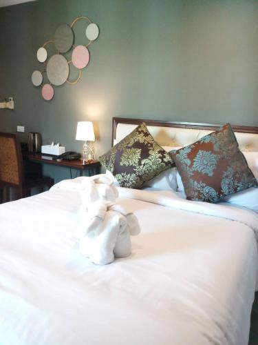 a stuffed animal sitting on top of a white bed at The Guest Hotel & Hostel in Chiang Mai