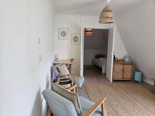 a living room with a chair and a bedroom at B&B Wijdzicht in Wolsum