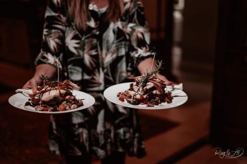 a woman holding two plates with food on them at Avoca River Cabins in Addo