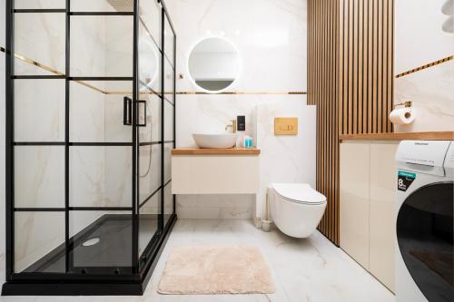 a bathroom with a shower and a toilet and a sink at Widzewska Deluxe Apartment by BookingHost in Łódź