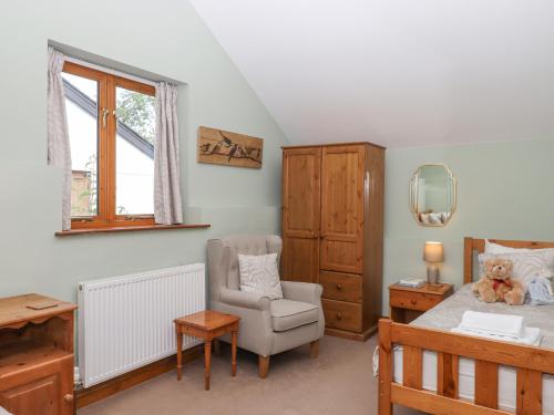 a bedroom with a bed and a chair at Peace Cottage in South Molton