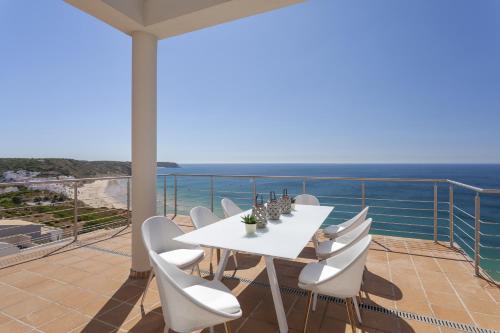 a white table and chairs on a balcony with the ocean at Villa Mar a Vista in Salema