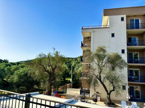a building with chairs and trees in front of it at Akhdar Apartments in Utjeha