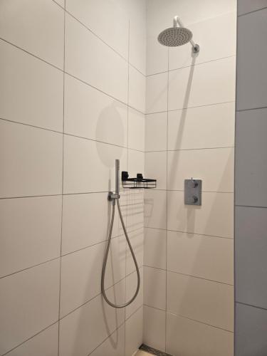 a shower with a hose in a white tiled bathroom at B&B Wijdzicht in Wolsum