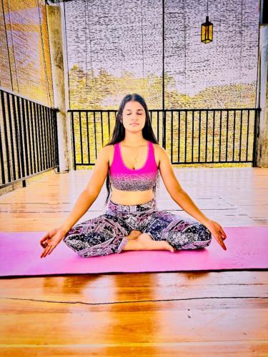 a woman is sitting on a pink yoga mat at Ceylon Ayu Resort Kandy in Kandy