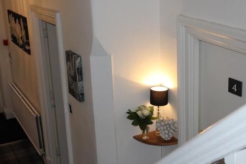 a hallway with a table with a lamp and flowers at St John's Lodge incl off-site leisure club in Windermere