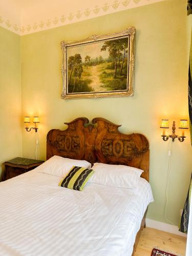 a bedroom with a white bed with a picture on the wall at Ēdoles Pils in Ēdole