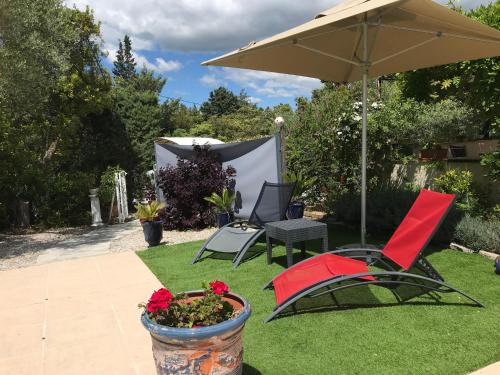 a patio with two chairs and an umbrella at Le Patio Fleuri in Lorgues