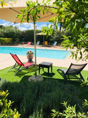 two chairs and an umbrella next to a pool at Le Patio Fleuri in Lorgues