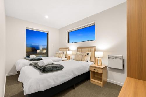 two beds in a bedroom with two windows at Starlet 11 in Lake Tekapo