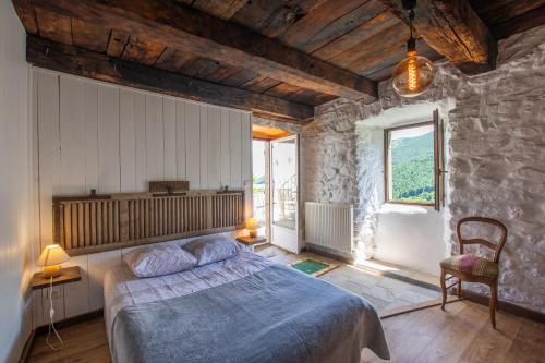 a bedroom with a bed and a stone wall at Les chambres de la ferme de chalas in Valgorge