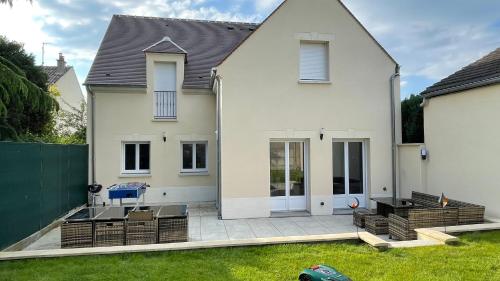 a white house with a patio in the yard at Magnifique villa 12 pers - 6 chambres avec salle de bain privative au Calme - 30 min Asterix - Ecrin de charme in Compiègne