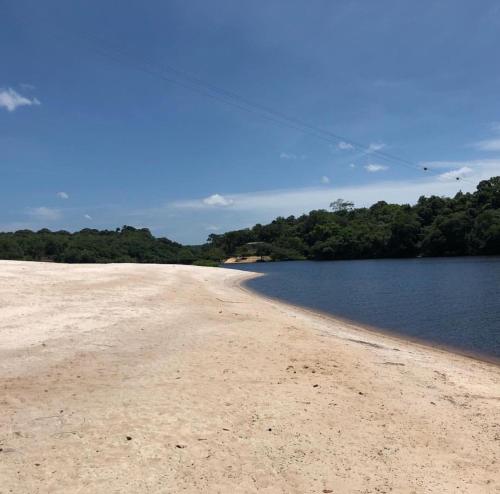 a sandy beach next to a body of water at Amazon Vibe in Colônia Paricatuba