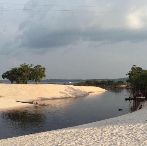 a body of water with a beach and trees in it at Amazon Vibe in Colônia Paricatuba