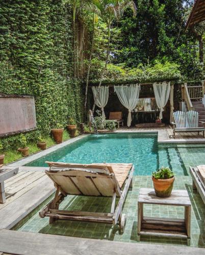 a swimming pool with a chaise lounge and a chair at Pousada Encantada in Trancoso