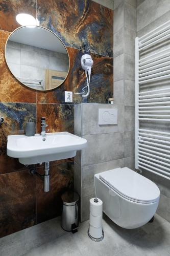 a bathroom with a sink and a toilet and a mirror at APARTMÁNY Sninský dvor in Snina