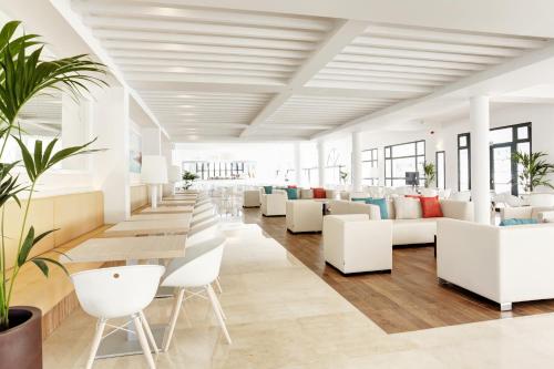 a waiting room with white chairs and tables at Grupotel Mar de Menorca in Es Canutells