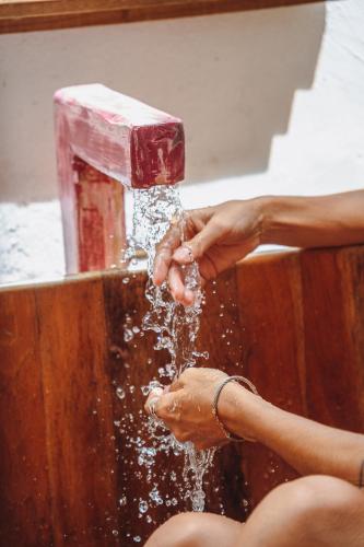 a person is washing their hands under a water fountain at Pousada Encantada in Trancoso
