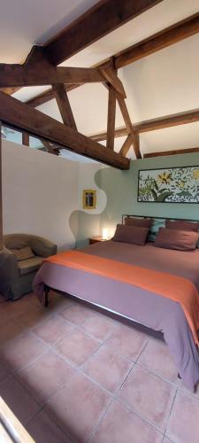 une chambre avec un grand lit dans une pièce avec des plafonds en bois dans l'établissement Gîte La Chaume, à Perrigny-sur-Loire