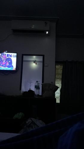 a dark room with a television and a couch at Mahesh Guest House in Hampi