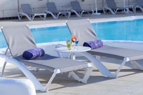 two chairs and a table next to a swimming pool at Eurostars Las Salinas in Caleta De Fuste