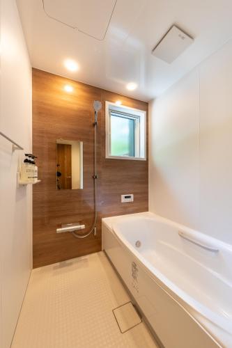 a bathroom with a bath tub and a window at 森の宿り 土庵まるやま in Nasu