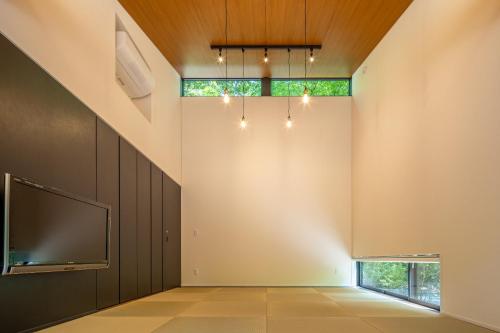 an empty room with a tv and a window at 森の宿り 土庵まるやま in Nasu