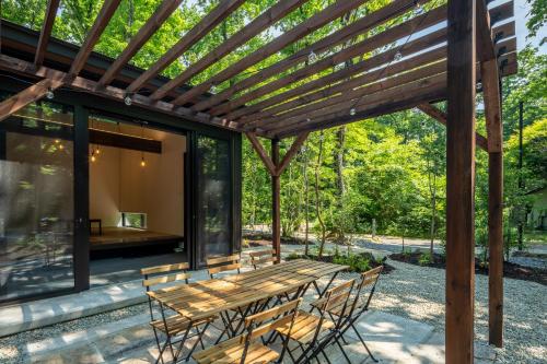 a wooden table and chairs under a wooden pergola at 森の宿り 土庵まるやま in Nasu