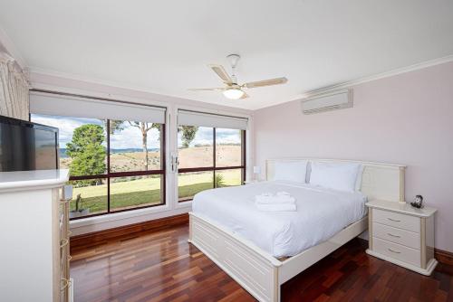 una camera bianca con un letto e una grande finestra di Goldfields View a One Tree Hill