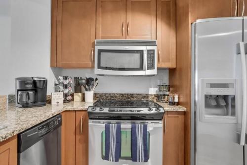 a kitchen with a stove and a microwave at Stylish 1BR Condo Rooftop Pool Close to Beach in Boynton Beach