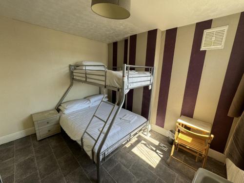 a bedroom with two bunk beds and a chair at Clacton Guest House in Clacton-on-Sea