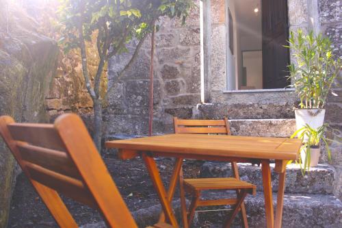 a wooden table and chairs next to a building at Casa Vouzelinha in Vouzela