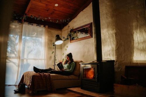 a woman sitting on a couch reading a book at Healesville Mud Brick Hideaway in Healesville